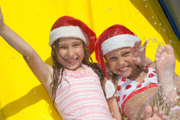 two cheerful little girls laughing and  playing in inflatable  pool splashing water