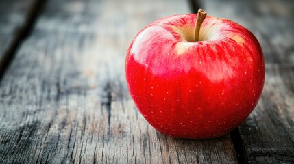 Wall Mural - A red apple on a rustic wooden table, the bright color standing out, symbolizing temptation and freshness.