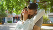 © Krakenimages.com - Woman and man embracing with joy in an urban park, showcasing love and happiness in a beautiful outdoor city setting with natural greenery around them