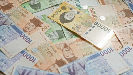 South korean banknotes scattered showcasing various denominations of won, emphasizing the detail and diversity of the currency.