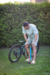 © Vitaliy - A man pumps up the tire of his bicycle in the park
