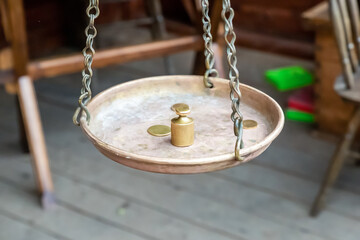 weight and gold coin on brass scales on a chain, scales close-up