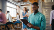 © Monkey Business - Smiling Businessman Using Digital Tablet Working In Busy Modern Open Plan Office