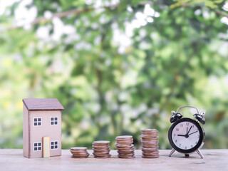 Poster - Black alarm clock, Miniature house and stack of coins. The concept of saving money for house, manage time to Property investment, House mortgage, Real estate.