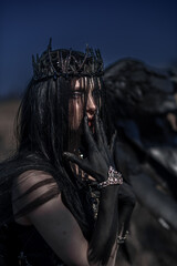 Goddess of death with black wings on a dried field