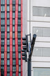 © yaqui_villegas - Close-up of a traffic light in front of a modern building with vivid red and white colors, illustrating urban regulation and architectural design.