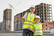 © Studio Peace - Portrait of a positive father and son in protective helmets on the background of a construction site