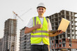 © Studio Peace - Architect works with a laptop on a construction site in a protective helmet and vest.