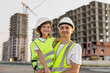 © Studio Peace - Portrait of a father and daughter in protective helmets on the background of a construction site.