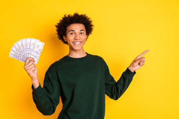 Wall Mural - Portrait of nice young man money direct finger empty space wear sweater isolated on yellow color background