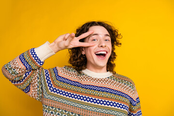 Sticker - Photo of nice good mood guy with wavy hairdo dressed ornament sweater showing v-sign symbol on eye isolated on yellow color background