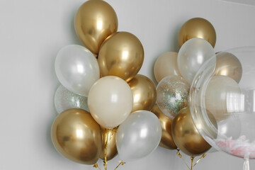 Shiny gold and white balloons, a large bunch of helium balloons.