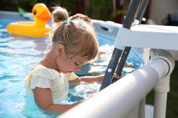 Sticker - Little girl getting out of swimming pool by ladder outdoors