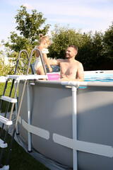 Poster - Happy father and her daughter resting in swimming pool outdoors