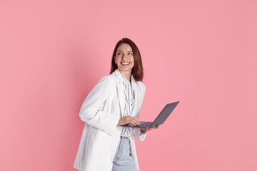 Canvas Print - Beautiful woman in stylish white jacket with laptop on pink background