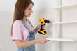 © New Africa - Woman with electric screwdriver assembling ladder shelf indoors