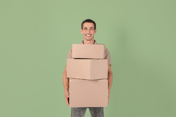 Wall Mural - Moving into new house. Man with cardboard boxes on light green background, space for text