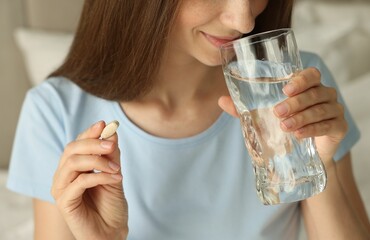 Sticker - Woman with glass of water taking pill at home, closeup