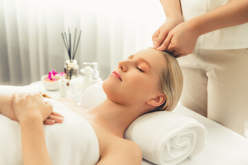 Caucasian woman enjoying relaxing anti-stress head massage and pampering facial beauty skin recreation leisure in dayspa modern light ambient at luxury resort or hotel spa salon. Quiescent