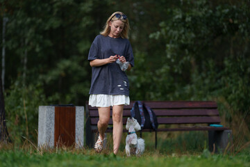 Girl walking the dog in the park forest. Rest concept. Woman walking with a dog on a leash during a good day