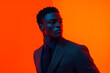 © Blockbits - Trendsetting Men in Dark Gray Suit with Solid Neon Orange Background Fashionable Portrait