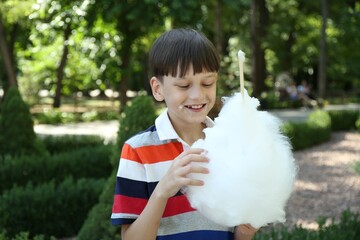 Wall Mural - Portrait of little boy eating sweet cotton candy in park