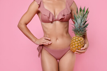 Wall Mural - Woman in stylish bikini with fresh pineapple on pink background, closeup