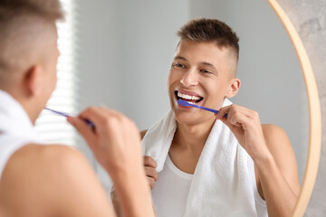 Canvas Print - Young man brushing his teeth in bathroom