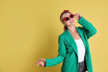 Poster - Beautiful woman in stylish green jacket on yellow background, space for text