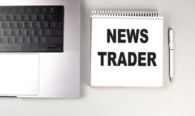 Poster - Notebook with the text news trader placed next to a laptop and pen on a desk