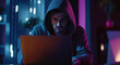 © Vitor - Um hacker de moletom com capuz senta-se em um laptop e olha para a tela. Segurança da informação, vulnerabilidade do sistema
