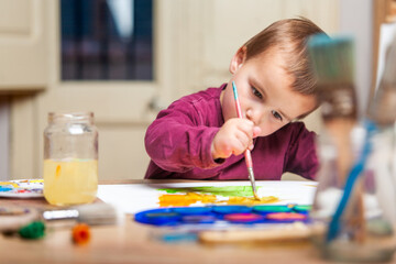 A young child is painting a picture with a brush