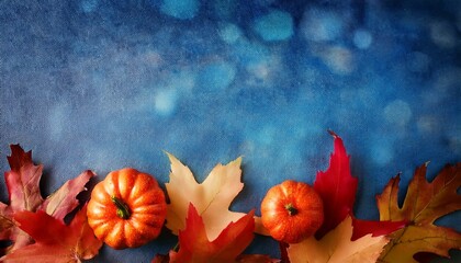 A vibrant blue background, resembling textured paper, features a border of colorful autumn leaves in deep red and golden yellow, with a small decorative pumpkin nestled among them.