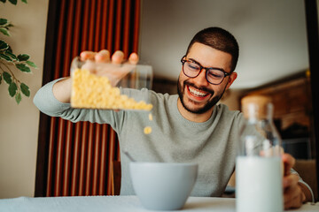 Young caucasian man eating corn flakes for breakfast at home