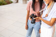 © ADDICTIVE STOCK - Two smiling young students experimenting with a camera outdoors