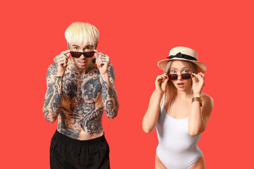 Canvas Print - Shocked young couple in sunglasses on red background