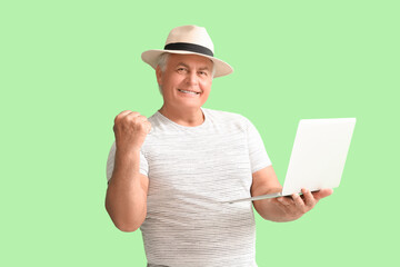 Wall Mural - Happy senior man with laptop on green background