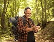 © Ljupco Smokovski - Mature male hiker with a backpack holding a mobile phone and typing