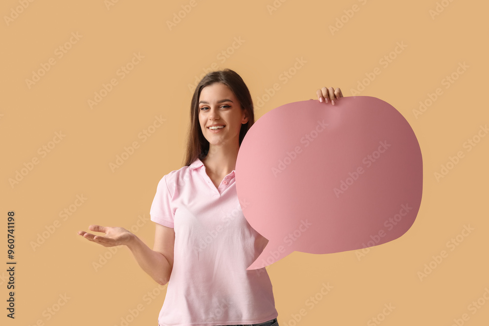 Beautiful happy young woman with speech bubble pointing at something on orange background