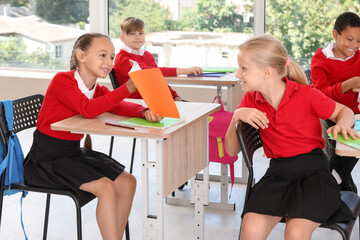 Poster - Little classmates sitting at desks during lesson in classroom