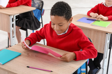 Poster - Little African-American schoolboy sitting at desk during lesson in classroom