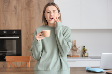 Sticker - Young woman with cup of hot coffee suffering from tooth ache at home