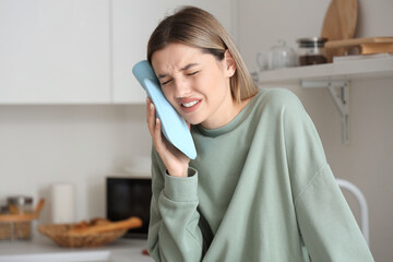 Sticker - Young woman with hot-water bottle suffering from tooth ache at home