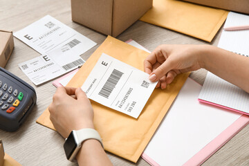 Sticker - Female postal worker sticking label to package on table, closeup