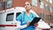 © VAKSMANV - Close up of Caucasian young professional woman nurse texting on tablet browsing online standing outdoor near ambulance. Beautiful female doctor in blue uniform tapping on device and looking away