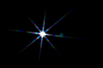 Wall Mural - star shaped lens flare on black background.