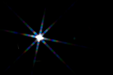 Wall Mural - star shaped lens flare on black background.
