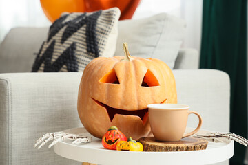 Wall Mural - Halloween pumpkins with with skeleton hands and cup of tea on bench at home