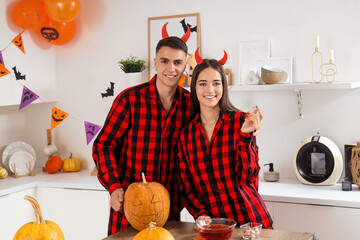 Sticker - Young happy couple in pajamas with pumpkin preparing for Halloween party at home