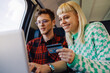© Zamrznuti tonovi - Happy passengers using laptop and credit card on a train during trip.